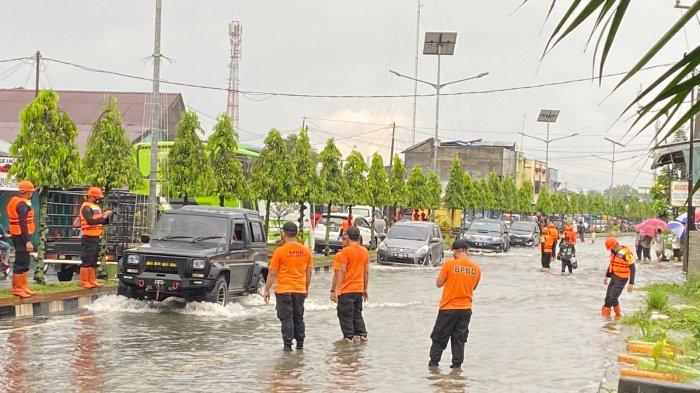BANJIR: Personel BPBD Kota Binjai memandu pengendara mobil supaya tidak terperosok ke lubang yang tergenang banjir, Rabu (11/5). (ISTIMEWA/SUMUTPOS)