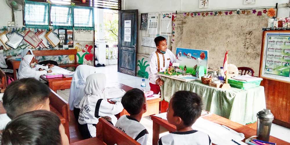 BERCERITA: Siswa kelas 5  SD Negeri 03 Tanah Merah, Kabupaten Batubara, saat bercerita mengenai terjadinya hujan, sembari memainkan diorama sebagai medianya dalam bercerita kepada adik kelasnya.