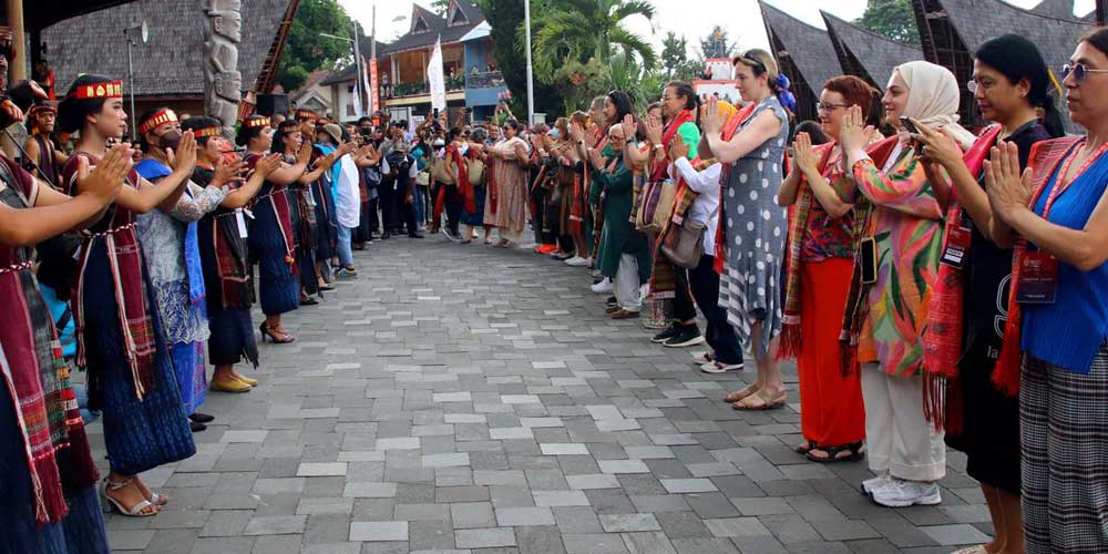 MANORTOR:  Para delegasi dari negara-negara peserta Women 20 (W20) Summit 2022 manortor bersama masyarakat sekitar saat mengunjungi destinasi wisata Huta Siallagan di Kabupaten Samosir, Sumatera Utara, Rabu (20/7). Mereka juga mengagumi keindahan Danau To