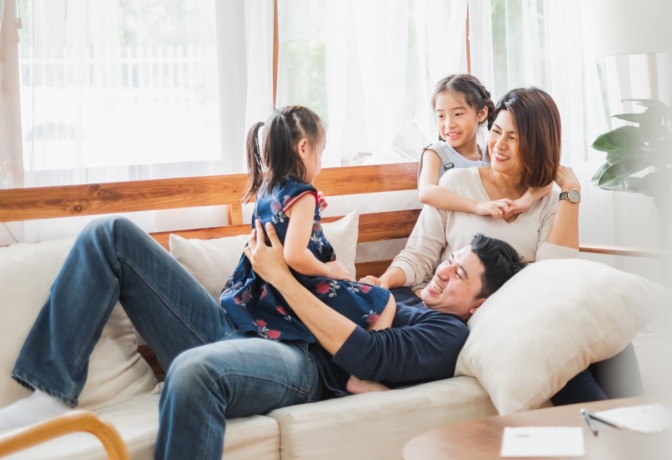 Happy Asian family playing together at sofa, home living room
