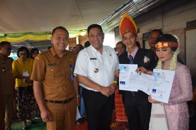 SERAHKAN: Bupati Dairi Eddy Keleng Ate Berutu didampingi Kepala Disdukcapil Deddy Situmorang, saat menyerahkan akta nikah kepada satu pasangan yang melangsungkan pernikahan di Desa Bunturaja, Kecamatan Siempat Nempu, Senin (24/10).Istimewa.