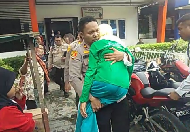 SIGAP: Kapolsek Medan Timur Kompol Rona Tambunan, dengan sigap menggendong seorang nenek yang pingsan menuju ambulans untuk dilarikan ke rumah sakit, Minggu (6/11).