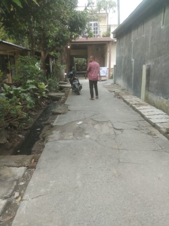 RETAK: seorang warga menunjukkan badan jalan yang kondisinya sudah retak-retak.