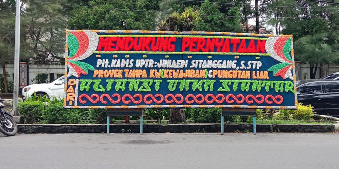 DUKUNGAN: Sejumlah kendaraan melintas di samping deretan papan bunga yang memberikan dukungan atas pernyataan Plt Kepala Dinas PUPR Pematangsiantar Junaedi Sitanggang, di depan Kantor DPRD Pematangsiantar, Rabu (1/3).Pra Evasi/Sumut Pos.