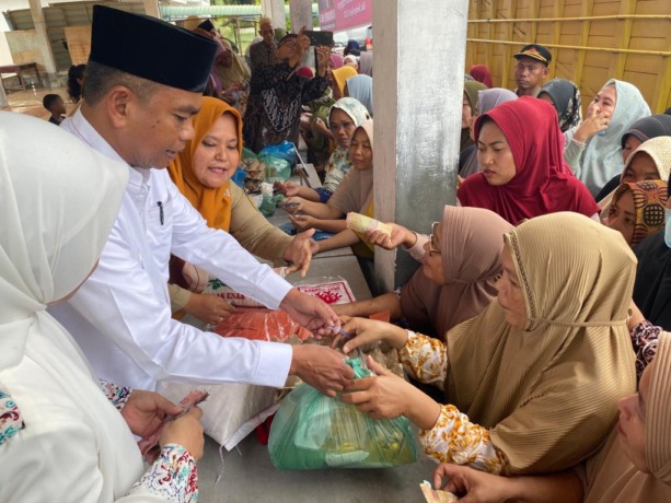 LAYANI: Bupati Sergai Darma Wijaya didampingi Ketua TP PKK  Hj. Rosmaida Saragih saat melayani ratusan masyarakat di pasar murah.