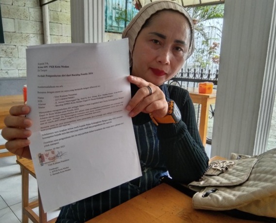 Umi Kalsum Nasution menunjukkan surat pengunduran dirinya kepada wartawan.