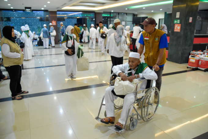 Refinaldi Setiawan/sumutpos JAMAAH LANSIA: Petugas membantu calon jamaah haji lanjut usia (lansia) yang duduk di kursi roda saat di Bandara Kualanamu.