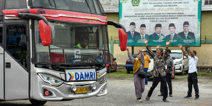 BERANGKAT: Keluarga calon jamaah haji asal Langkat melambaikan tanggan kepada calon jamaah haji di dalam bus yang akan berangkat menuju bandara dari Asrama Haji Jalan A. H. Nasution Medan, Minggu (4/6).