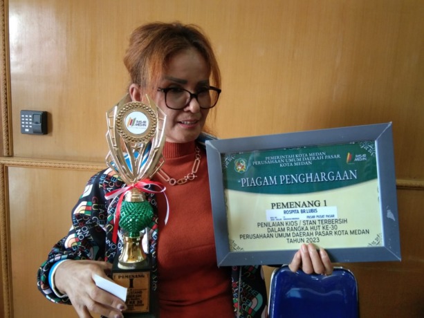 KIOS TERBERSIH: Seorang pedagang di Pasar Pusat Pasar, Rospita br Lubis, saat menerima penghargaan dari PUD Pasar Kota Medan, sebagai Kios Terbersih di Kota Medan - Istimewa.