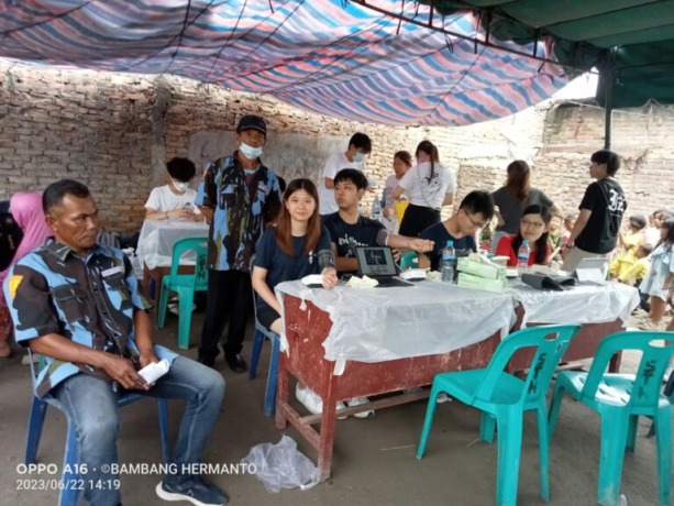 PERIKSA: Mahasiswa Kedokteran CUHK Hongkong saat melakukan pemeriksaan kesehatan kepada warga Belawan 1, Jumat (23/6/2023).