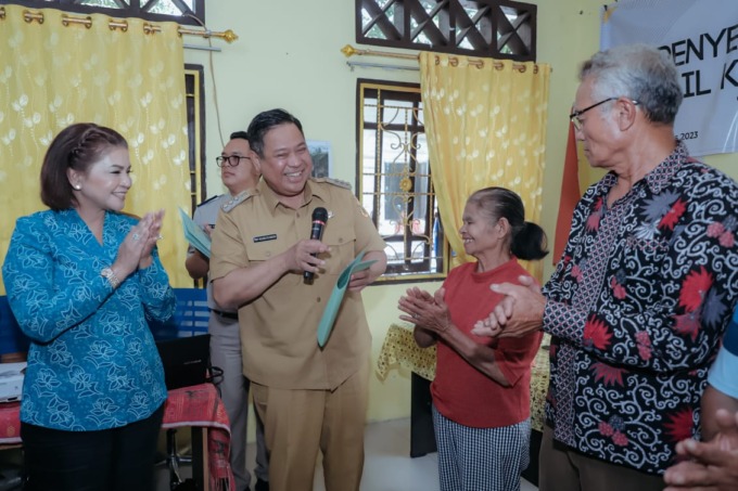 SERAHKAN: Bupati Dairi, Eddy KA Berutu didampingi Ketua TP PKK, Ny Romy Mariani Simarmata menyerahkan sertifikat tanah kepada warga di Kecamatan Sitinjo.Istimewa.