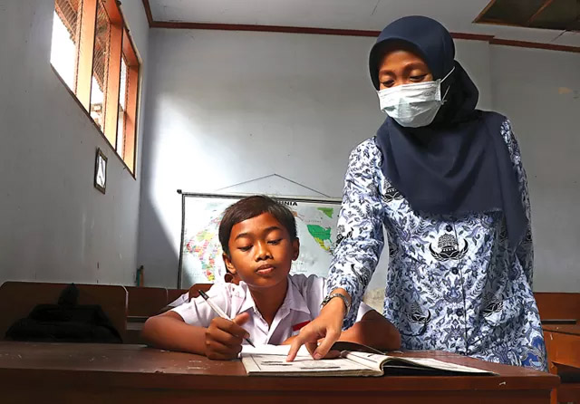 MENGAJAR: Seorang guru membimbing siswa SD dalam proses belajar mengajar. Tahun ini, sebanyak 50.281 guru P1 dipastikan terserap.