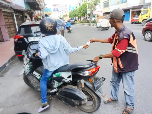 KARCIS: Jukir saat memberikan karcis kepada pengendara di Jalan Jenderal Sudirman, Binjai Kota.Istimewa/Sumut Pos.