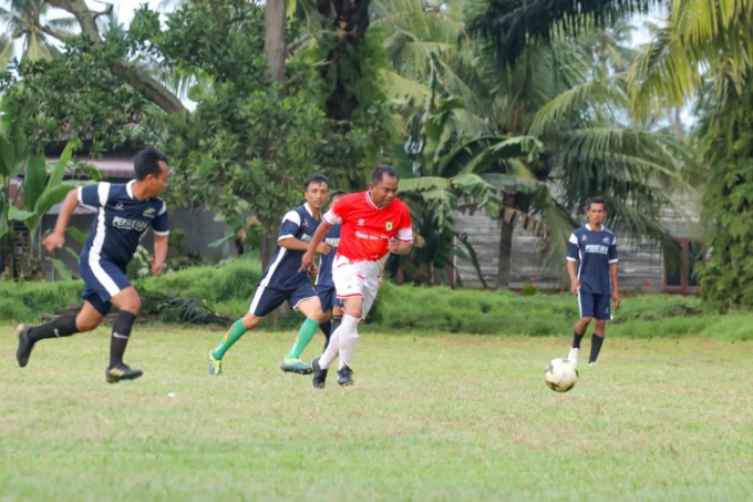 Bupati Sergai H Darma Wijaya berusaha melewati hadangan tiga pemain Tim Pemdes Tanah Raja.  (Fadly/Sumut Pos)