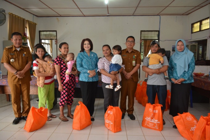 BANTUAN NUTRISI: Kepala Dinas Kesehatan Dairi Henry Manik, dan Ketua TP PKK Dairi Romy Mariani Simarmata, diabadikan bersama masyarakat penerima bantuan nutrisi program penurunan stunting.