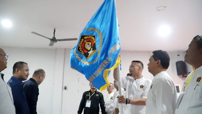 BENDERA: M Darwis Sinulingga mengibarkan bendera petaka usai terpilih sebagai Ketua PWI Langkat periode 2023-2026.Istimewa/Sumut Pos.