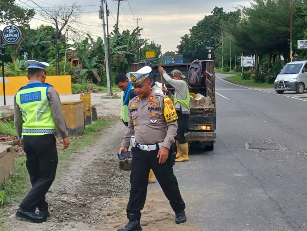 TIMBUN: Kasatlantas Polres Sergai AKP Andita Sitepu bersama personel saat lakukan penimbunan. (humas polres sergai).
