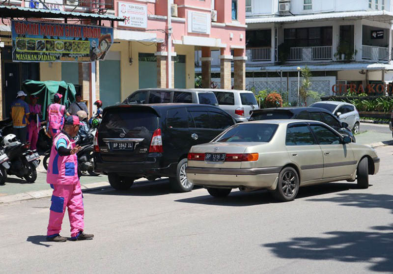 Seorang juru parkir mengenakan seragam aru berwarna ping dari Dinas Perhubungan Kota Batam mengatur kendaraan yang akan parkir di kawasan Greeend land Batamcenter, Selasa (14/5). F Cecep Mulyana/Batam Pos