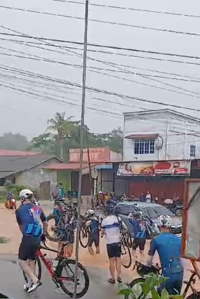 sejumlah bule mengangkat sepeda saat melewati jalan yang banjir