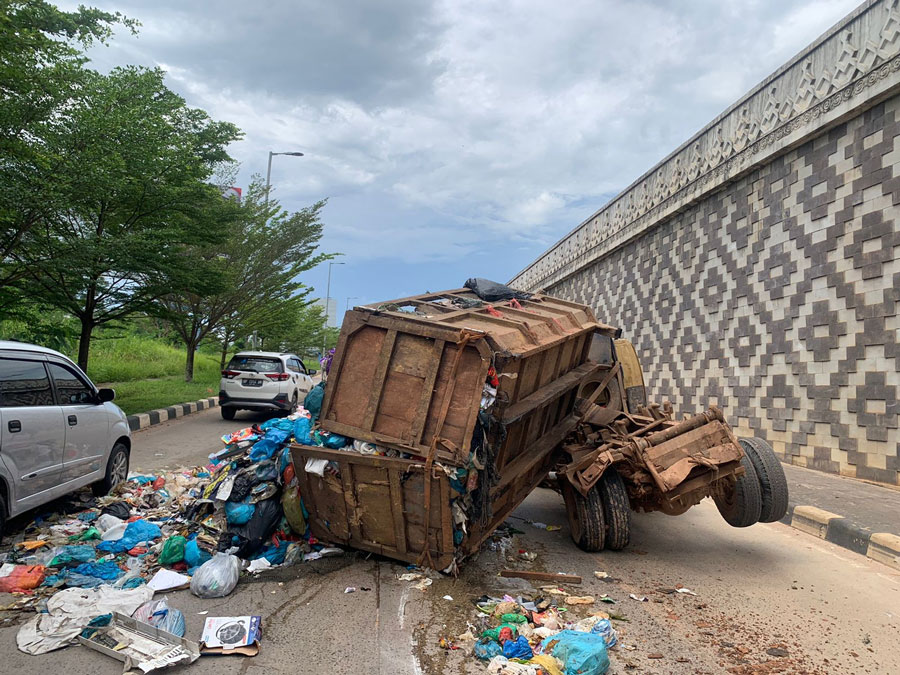 Satu unit truk armada pengangkutan sampah  terbalik dan muatan sampahnya tumpah ke Jalan Sudirman di samping Flyover Laluan Madani, Batam Center, Kamis (30/5).