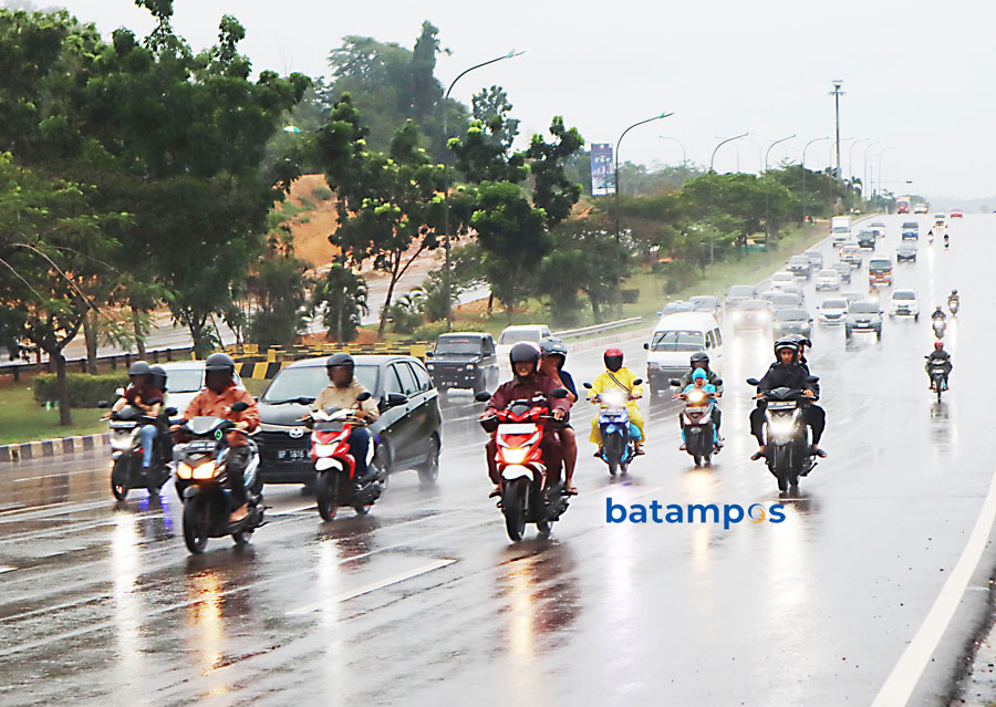 Sejumlah pengendara sepeda motor mengenakan jas hujan untuk melindungi dari guyuran hujan di wilayah Batam Kota, Minggu (2/6). Curah hujan cukup tinggi dalam sepekan ke depan.