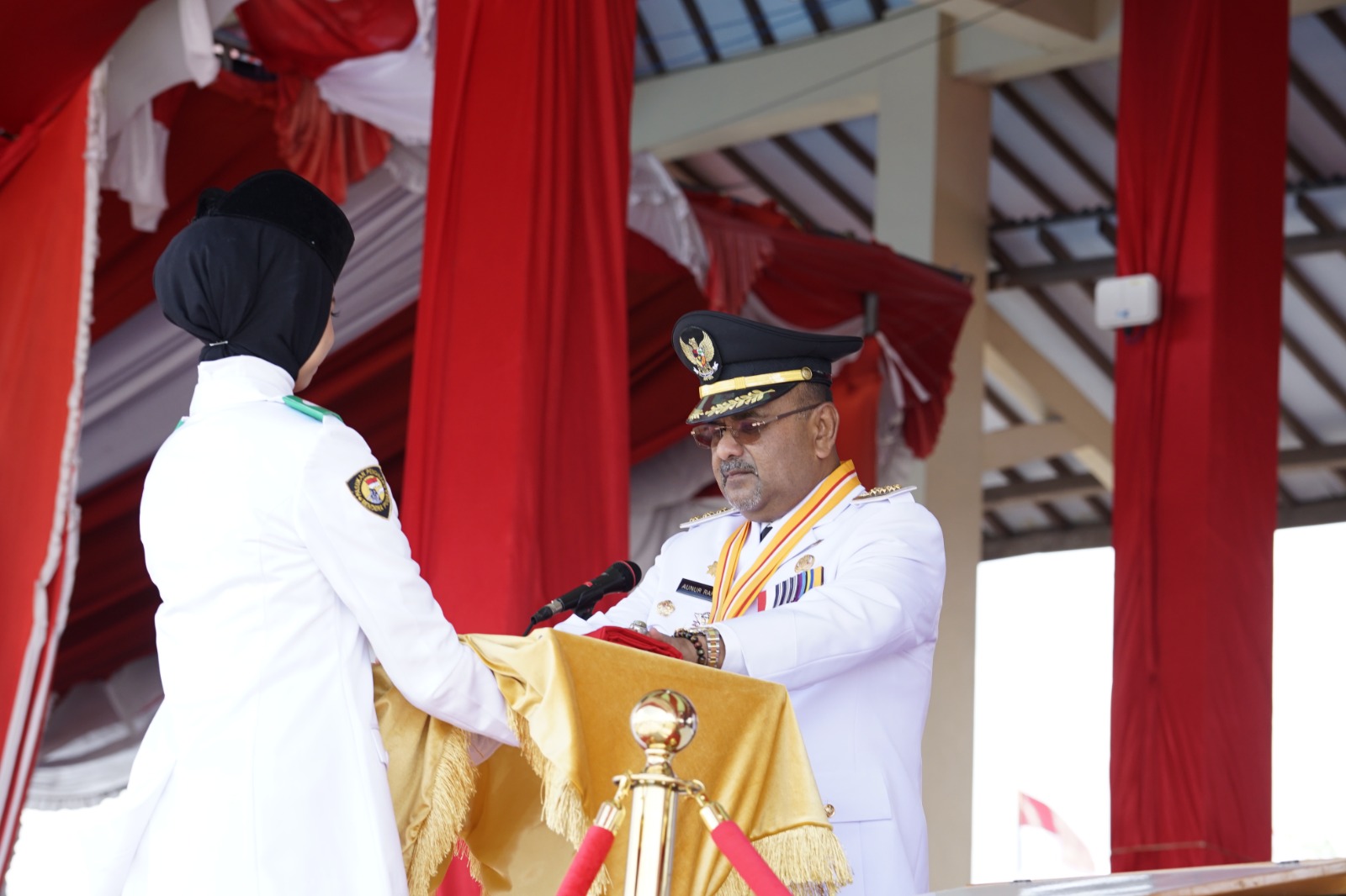 Bupati Karimun Aunur Rafiq ketika menyerahkan bendera merah putih kepada Ifta Laili Nur