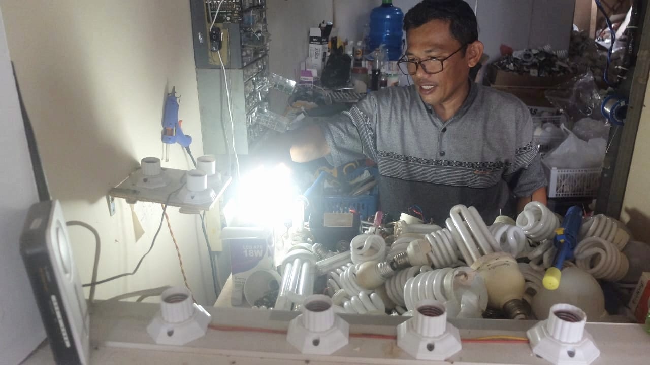 Mahyunis tengah memperbaiki lampu rusak milik pelanggan di klinik Dokter Lampu Tanjungpinang.