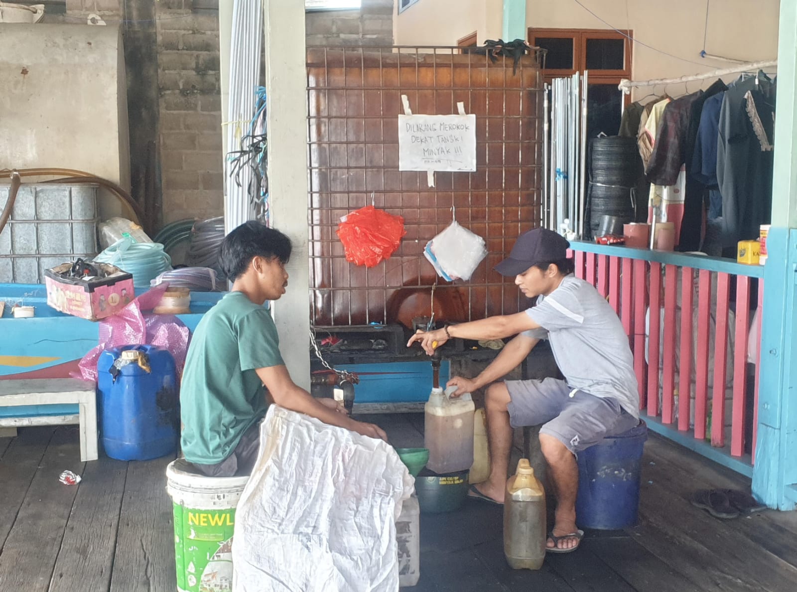 Dua orang pekerja di penyalur Putra Bersaudara, Desa Tarempa Barat sedang mengisi solar subdisi ke jerigen milik nelayan