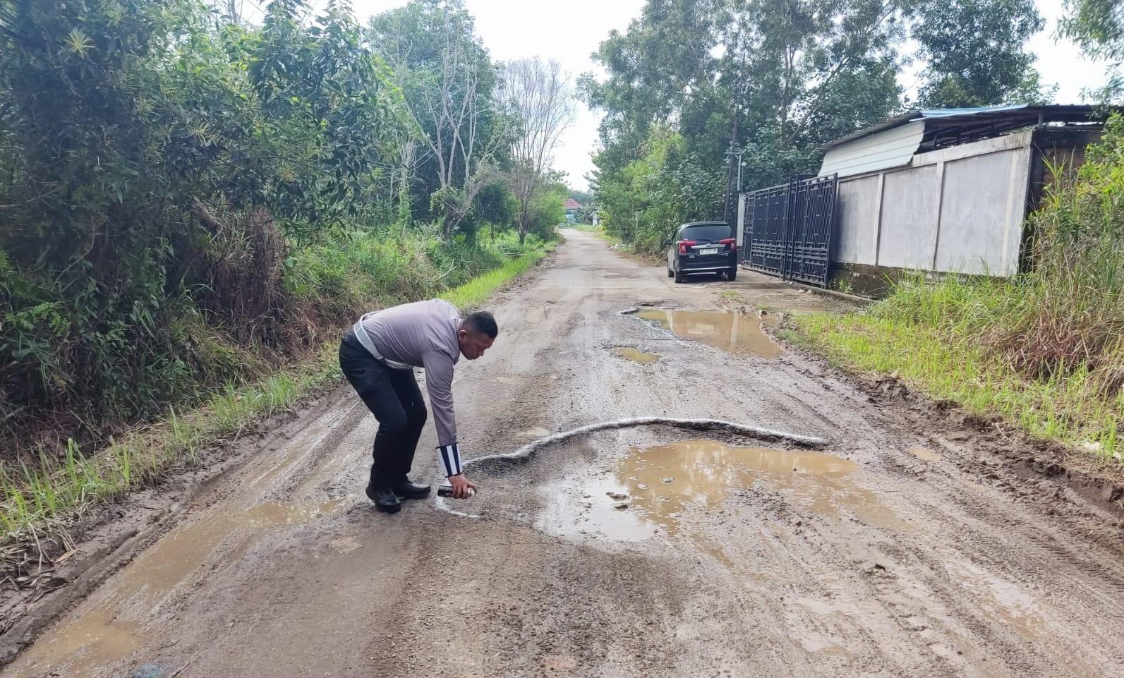 Petugas Polisi Lalu Lintas memberi tanda di lokasi jalan berlubang di jalan Bakti Sosial, Kelurahan Tanjunguban Selatan, Kecamatan Bintan Utara, Rabu (18/12/2024).