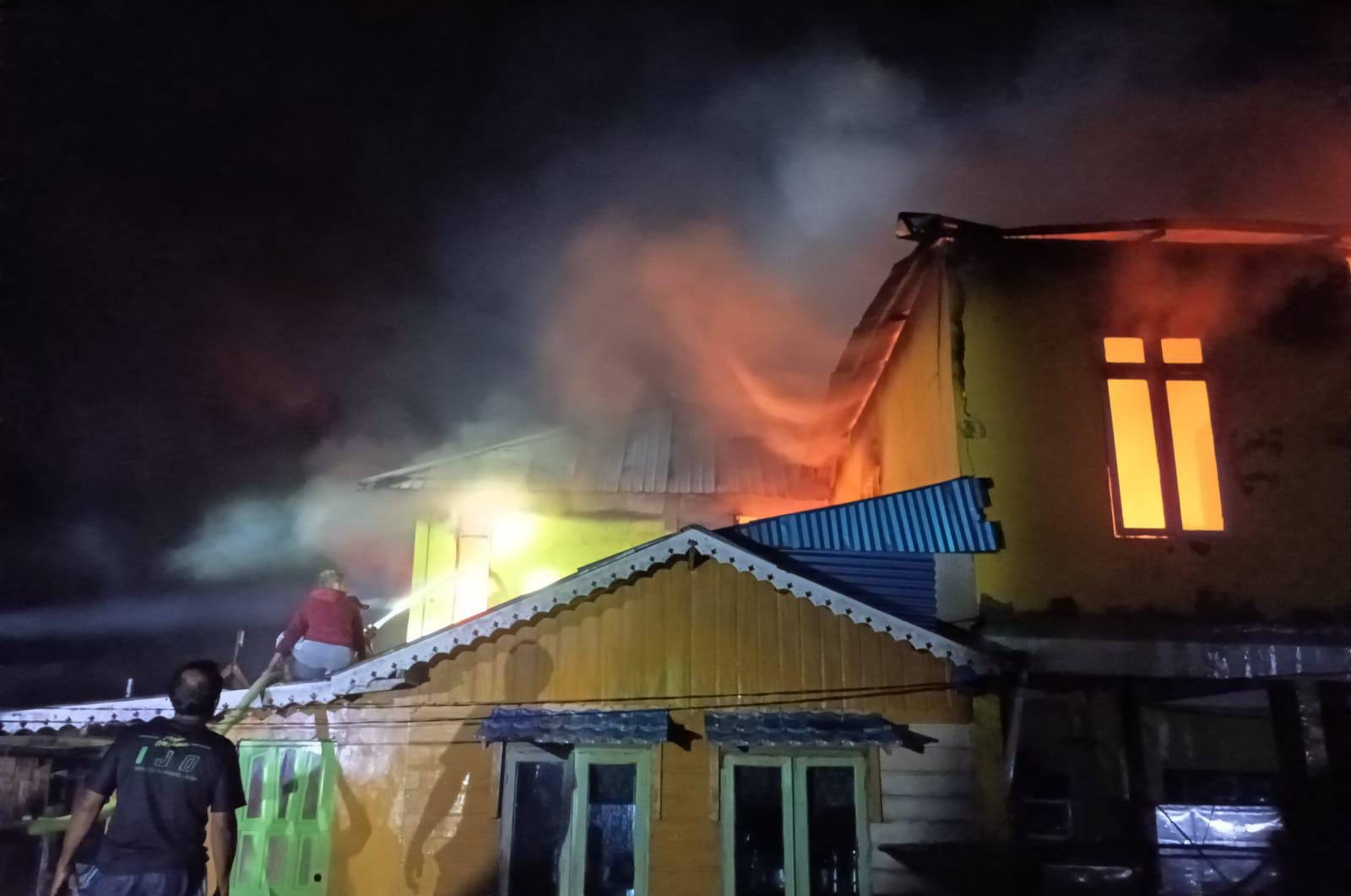 Petugas dibantu warga sedang mencoba memadamkan api yang menyerang rumah dua lantai milik Aswandi di Desa Nyamuk.