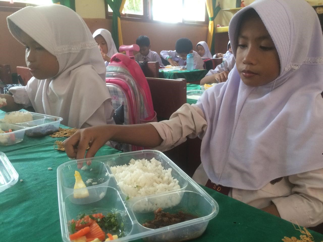 Para pelajar SDN 001 Tebing saat menyantap makanan bergizi gratis.