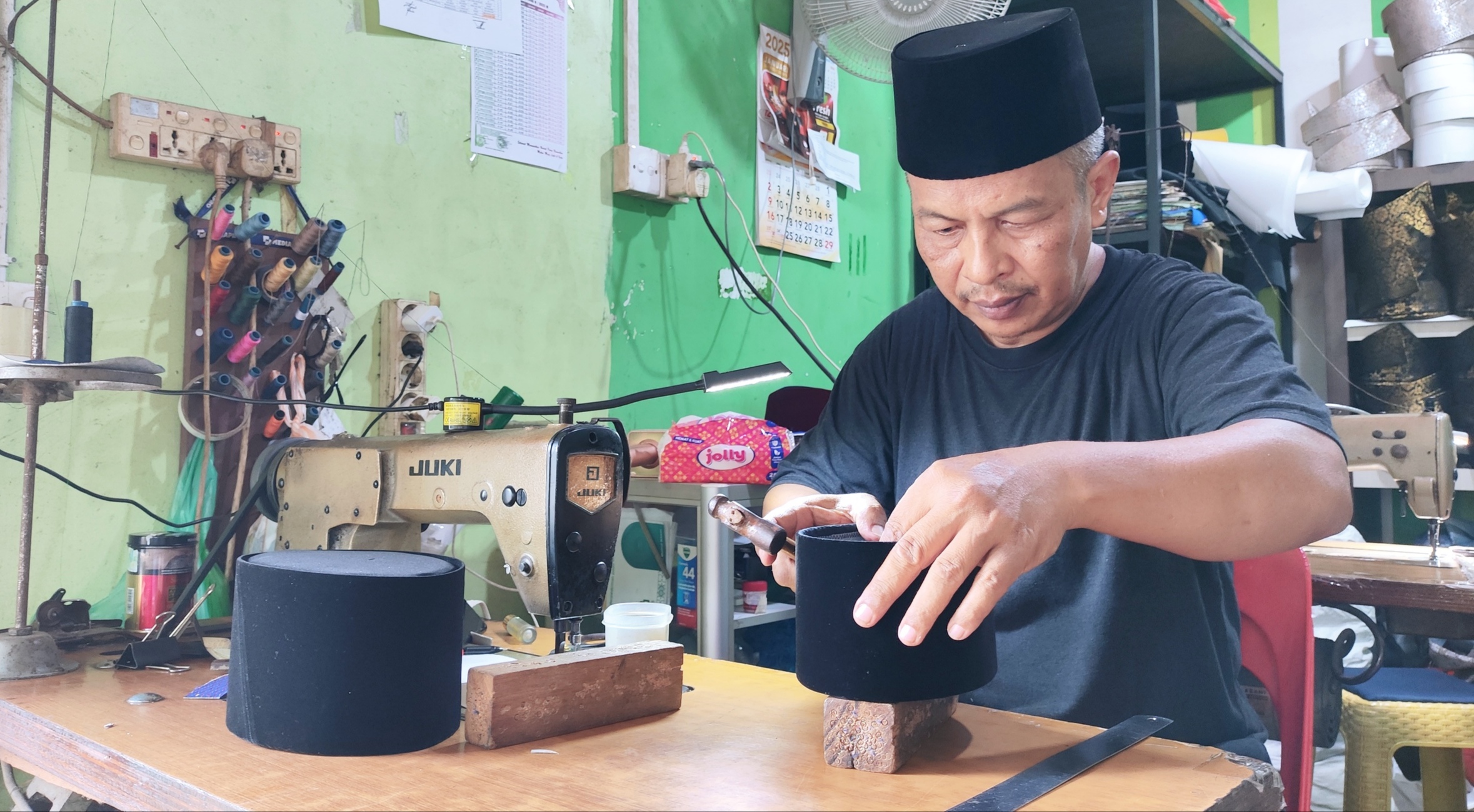 Syafran memproduksi songkok di gerai Gurindam Songkok Jalan Kuantan Tanjungpinang.