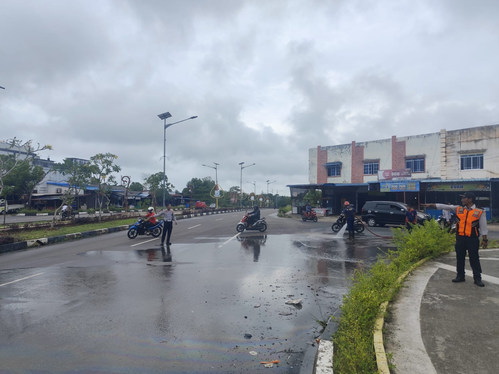 Petugas Damkar dan Dishub membersihkan tumpahan solar di simpang Jalan Ganet Tanjungpinang, Selasa (8/4).