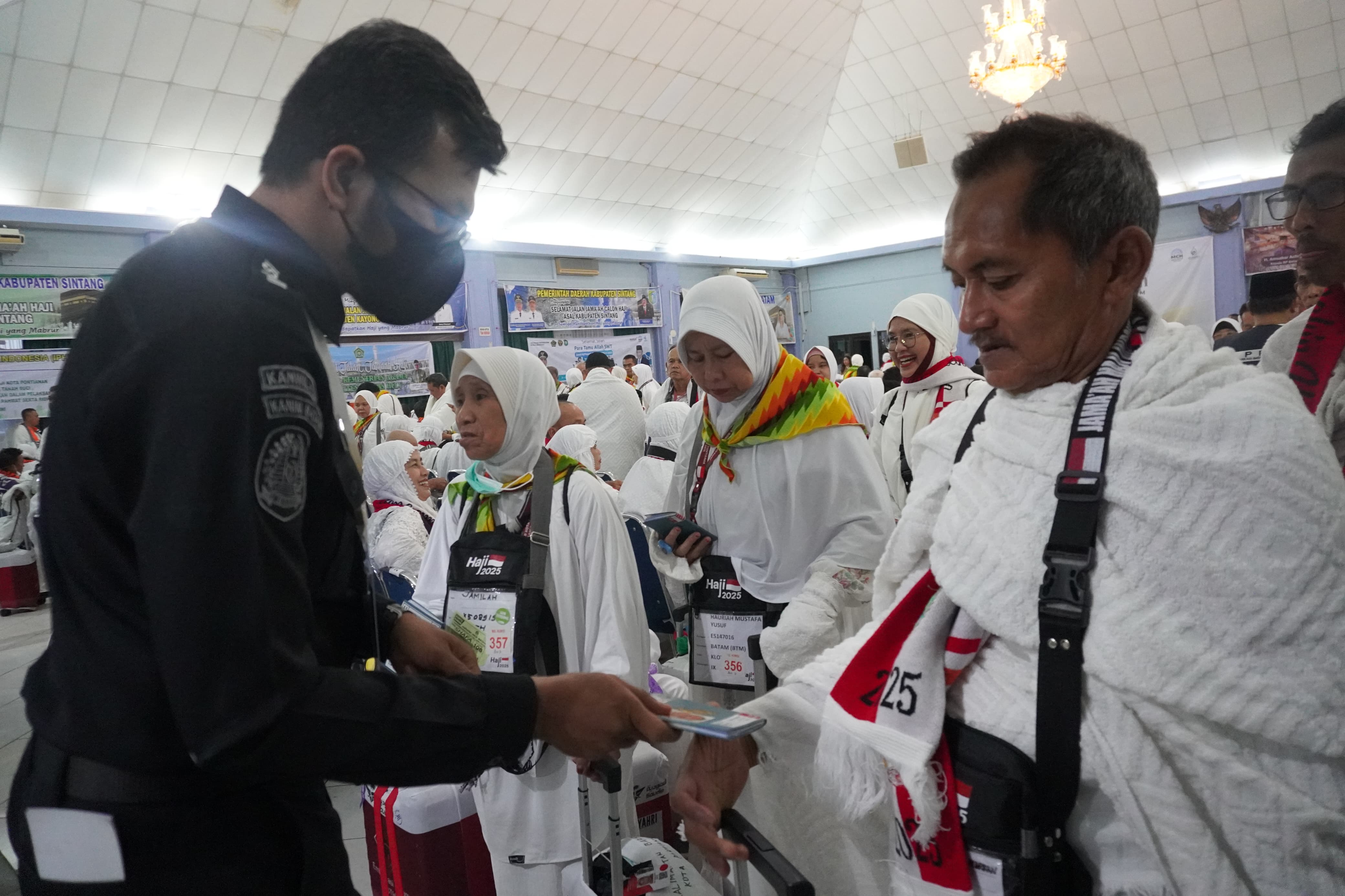 Petugas Penyelenggara Ibadah Haji (PPIH) Embarkasi Batam menyerahkan dokumen perjalanan kepada Jemaah Calon Haji (CJH) Kloter 27 menjelang pemberangkatan melalui Bandara Internasional Hang Nadim.