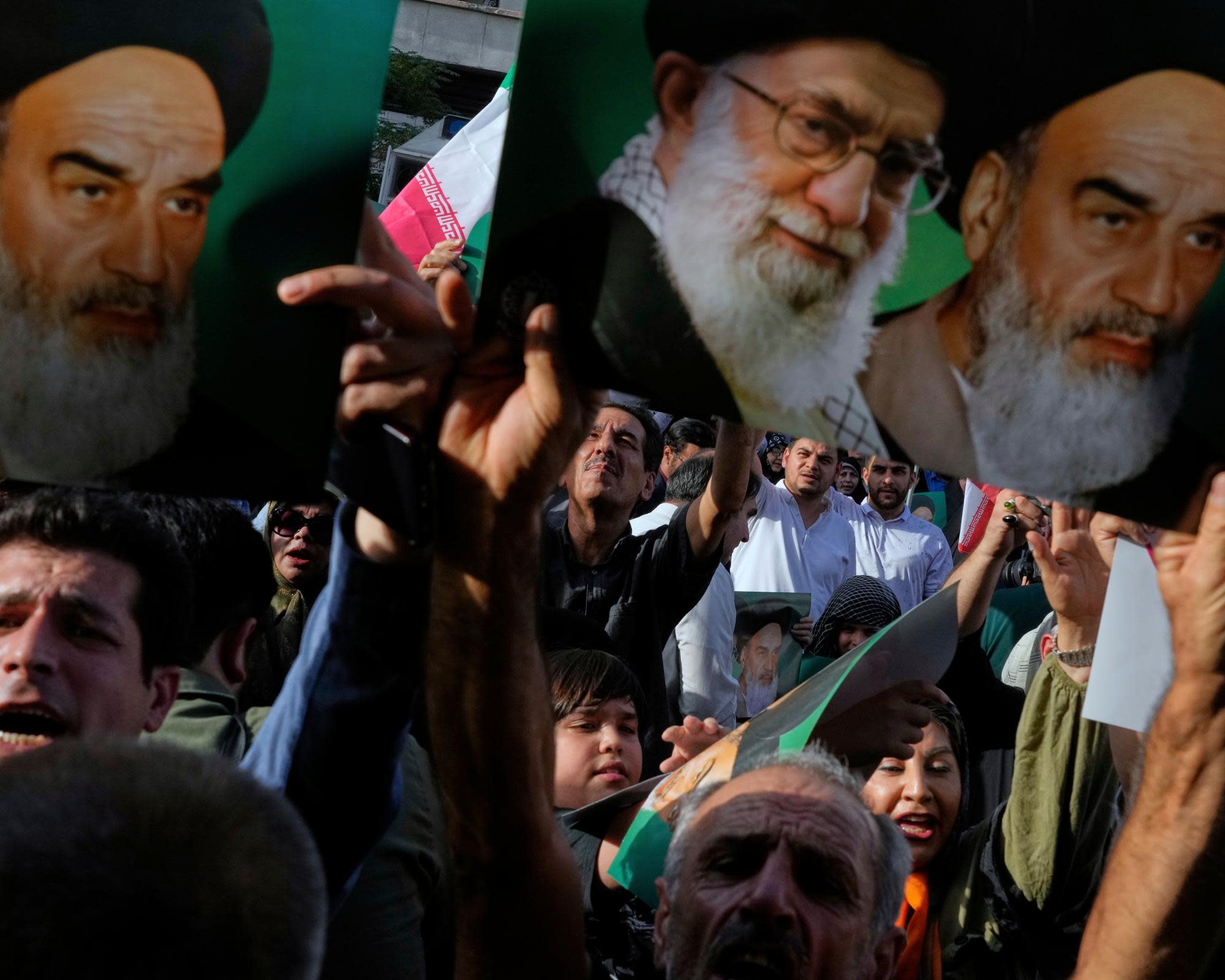 Para pengunjuk rasa di Teheran mengangkat poster bergambar Pemimpin Tertinggi, Ayatollah Ali Khamenei, dan mendiang Ayatollah Khomeini setelah serangan AS. F Vahid Salemi/AP via The Guardian