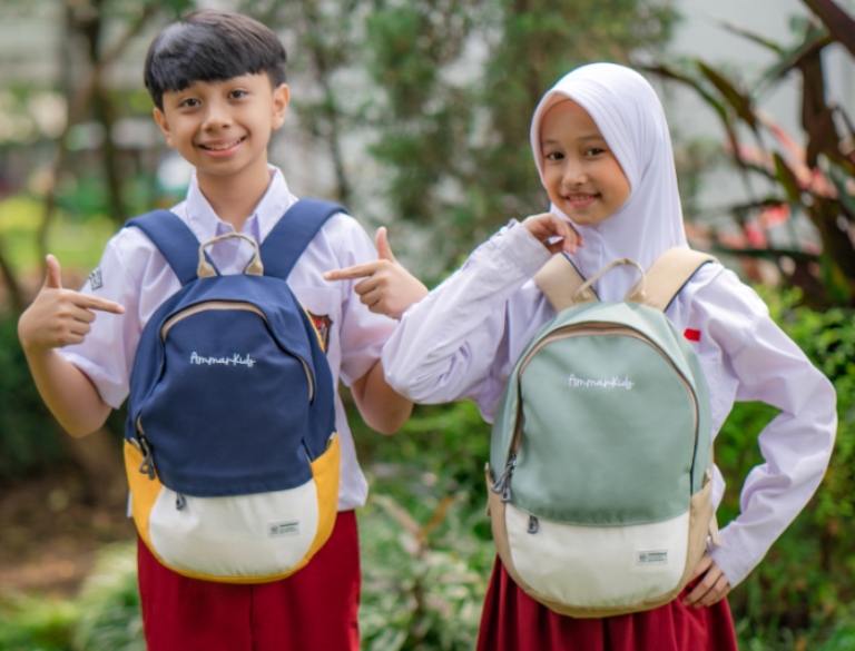 ILUSTRASI. Dua anak sekolah menunjukkan tas yang berisi perlengkapan belajar.