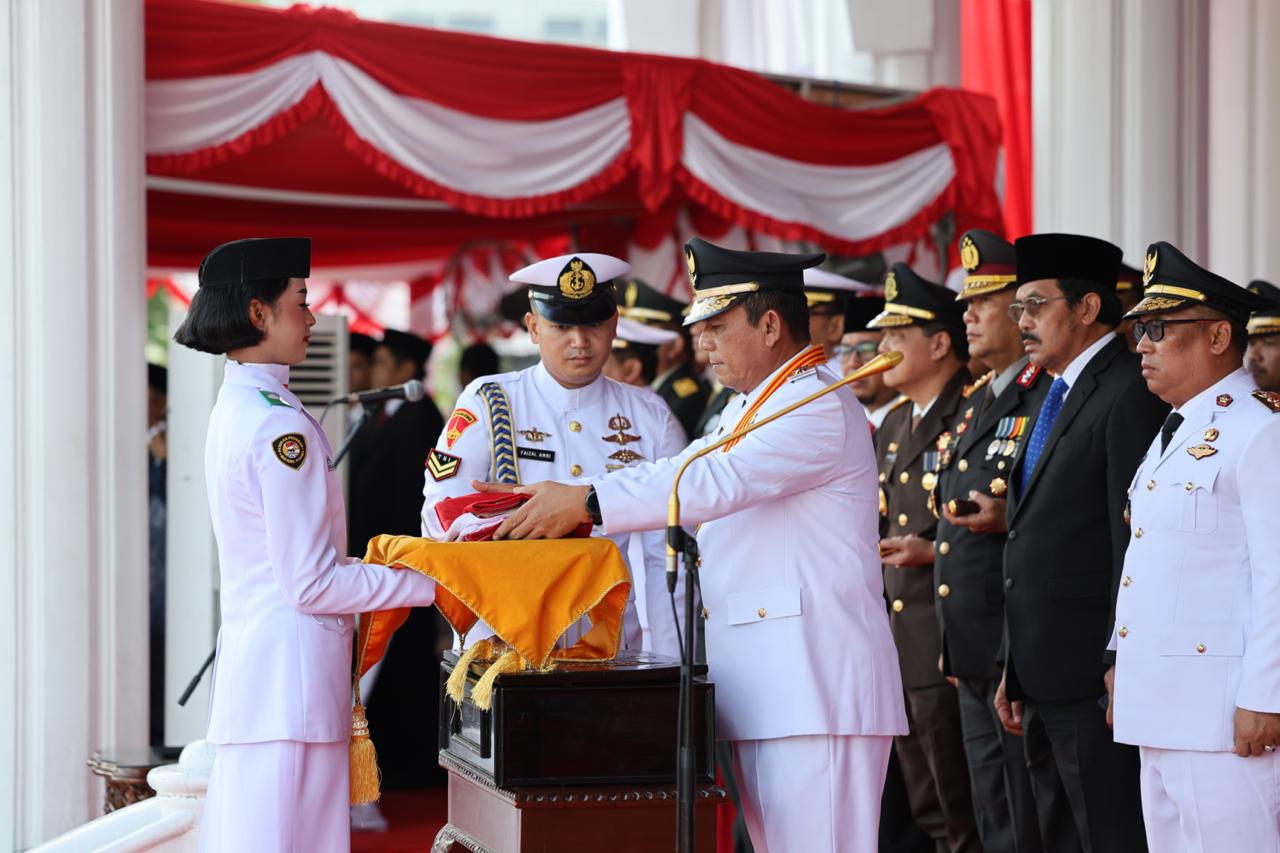 Ansar Ahmad yang bertindak sebagai Inspektur Upacara Peringatan HUT RI ke-80 tingkat Provinsi Kepri menyerahkan bendera merah putih kepada pembawa baki untuk dikibarkan.