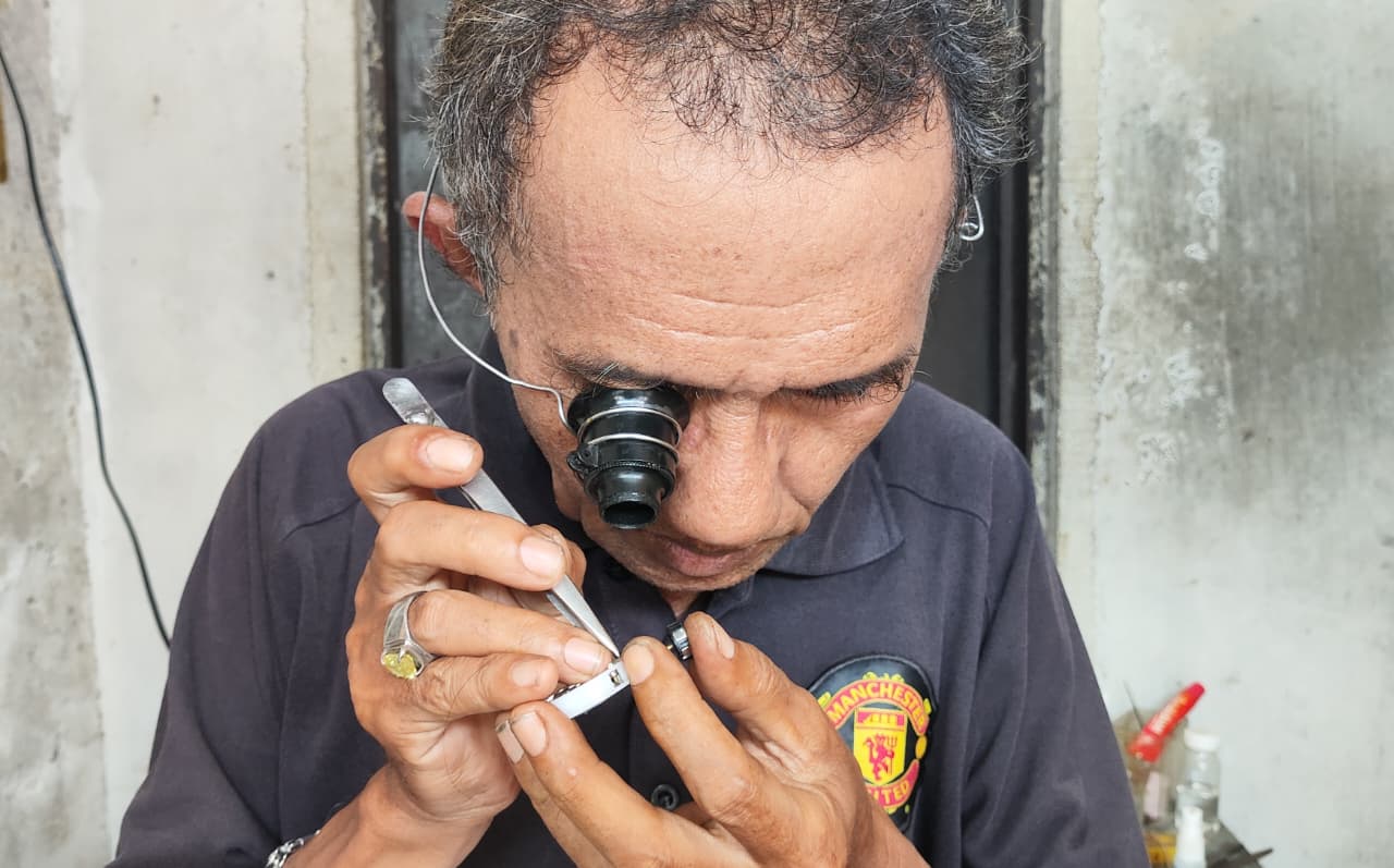 Gustiar tengah memperbaiki arloji milik pelanggannya di Kedai Arloji Pak Achyar Jalan Merdeka Kota Lama Tanjungpinang.