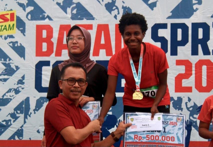 Kepala Dinas Pendidikan Kota Batam, Hendri Arulan, menyerahkan medali kepada juara nomor 100 meter SMA putri.