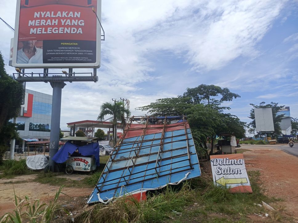 Papan reklame yang tumbang di jalan R Suprapto Sagulung.