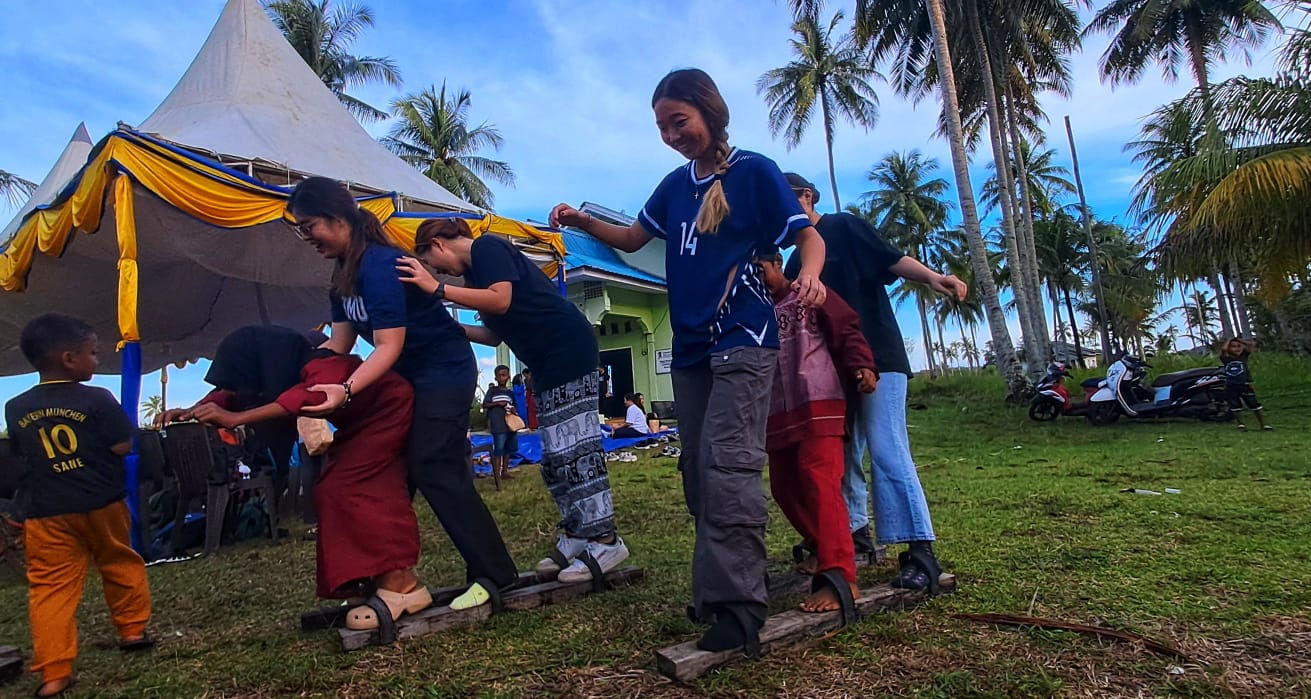 Mahasiswa Singapura bersama anak-anak dari masyarakat lokal melakukan permainan tradisional bakiak di Desa Pengudang, Kecamatan Teluk Sebong.