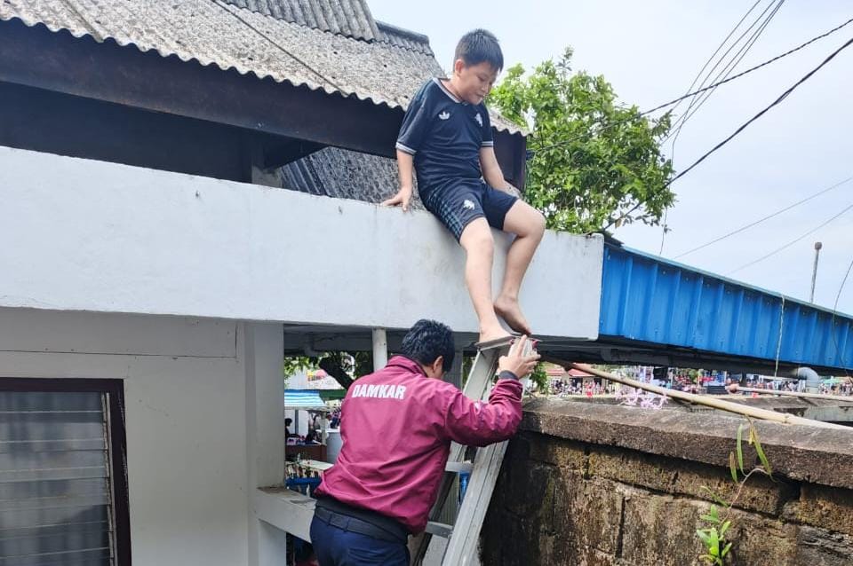 Seorang bocah, Adit (10) dievakuasi oleh petugas damkar dari atas Genteng.