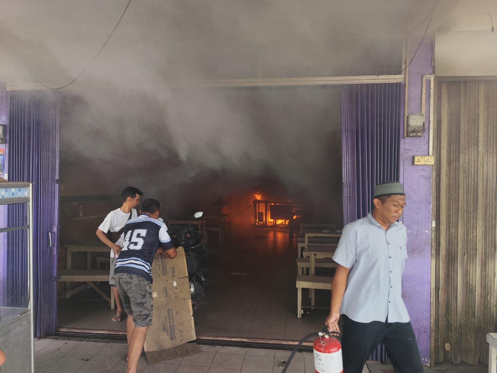 Warga sekitar saat berusaha memadamkan api yang melalap bagian dalam ruko di Jalan Wiratno Tanjungpinang, Minggu (13/10).