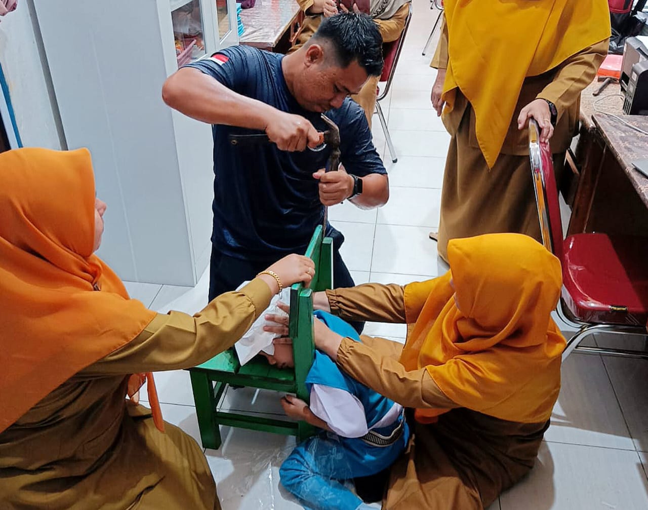 Petugas Damkar dibantu guru berusaha mengeluarkan kepala murid TK Pembina yang tersangkut di Kursi.