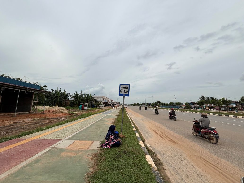 Tak ada fasilitas, warga yang menunggu bus transbatam hanya bisa duduk di rumput.
