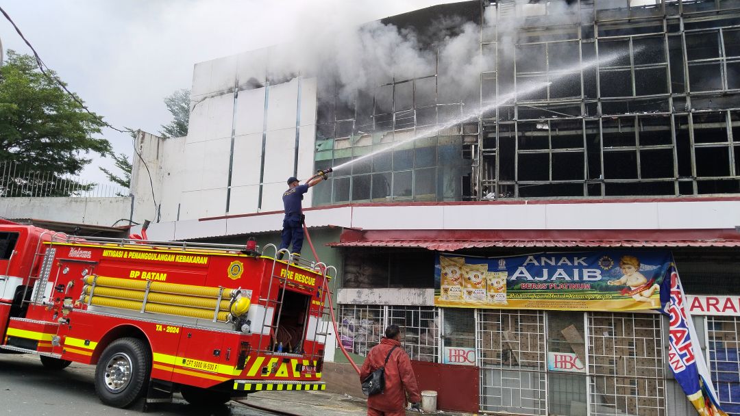 Petugas pemadam berusaha memadamkan api yang membakar toko sembako di Sekupang.