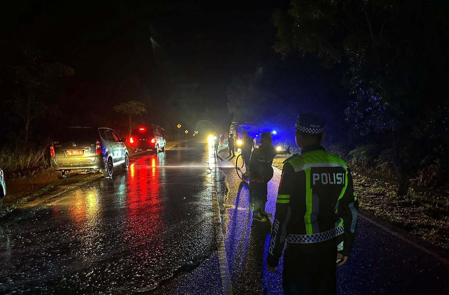 Petugas Kepolisian bersama Damkar Toapaya membersihkan jalan dari tumpahan minyak solar di jalan Lintas Barat, Bintan, Selasa (18/11) malam.