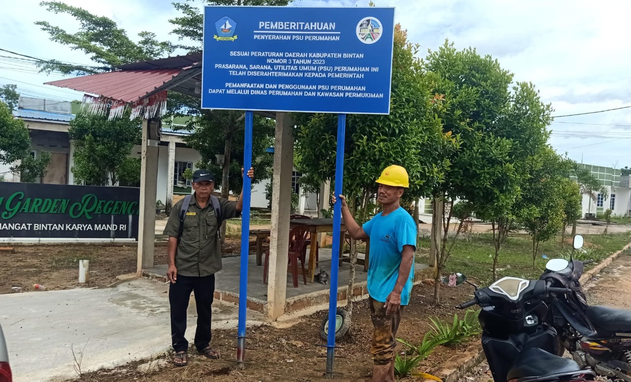 Pegawai dari Dinas Perkim Bintan dan warga memasang papan plang di salah satu perumahan yang telah menyerahkan PSU pada Rabu (26/11).