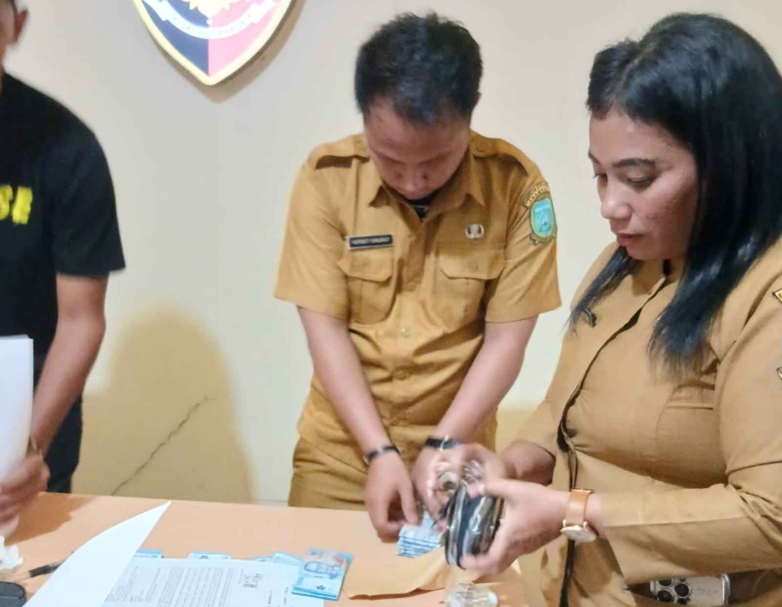 Pelapor, Deva (paling kanan) dibantu rekannya saat menghitung uang kompensasi di Polsek Siantan.