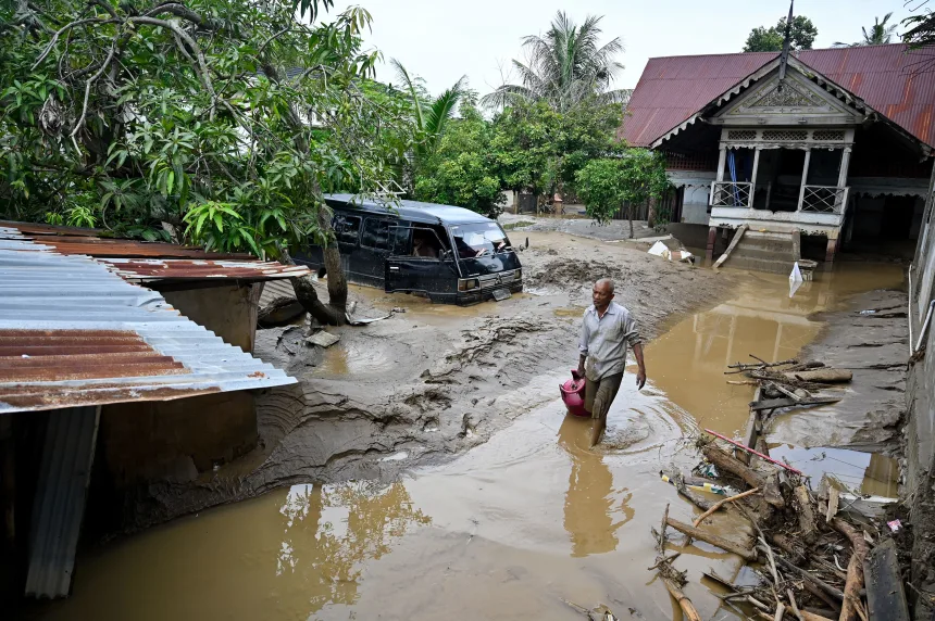 Seorang pria menerobos genangan air setelah banjir bandang melanda Meureudu, di Kabupaten Pidie Jaya, Aceh, pada 28 November lalu. F. Chaideer Mahyuddin/Getty Images via CNN